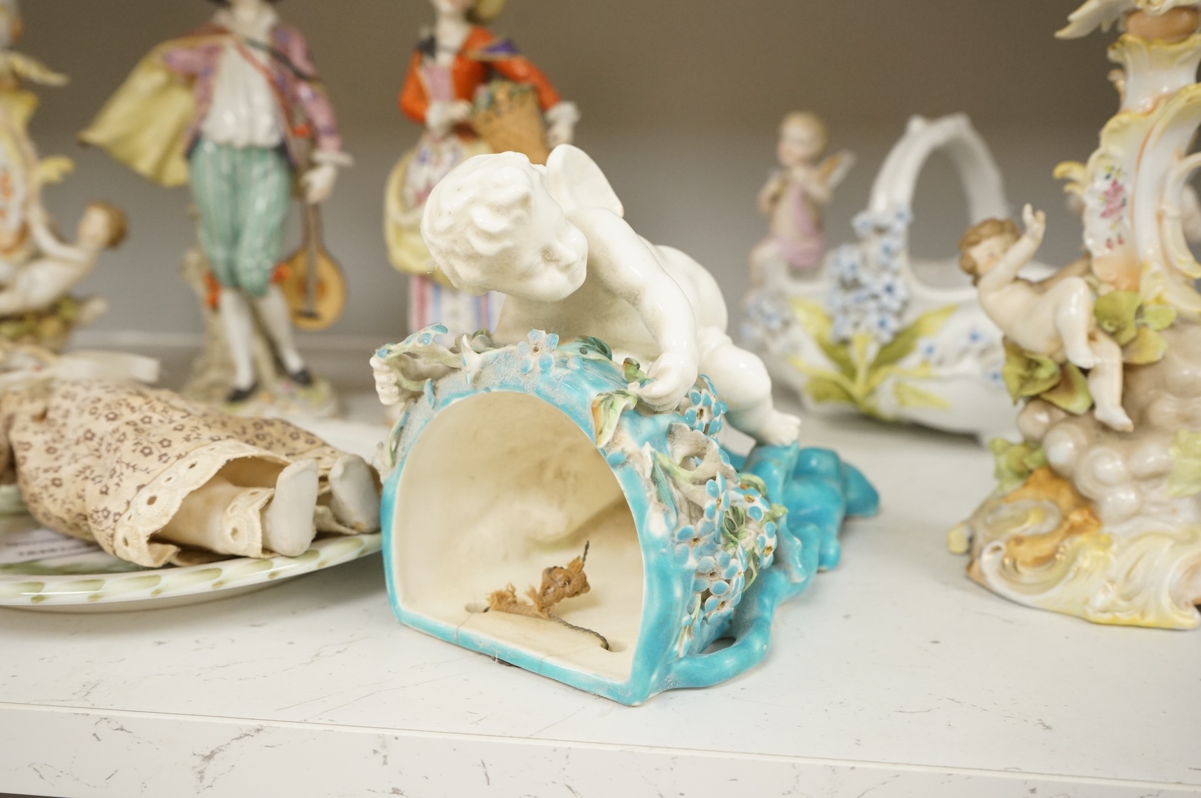 A pair of Sitzendorf figurines, damage to one, a pair of candlesticks, a Rye pottery dish, a Moore Bros. wall pocket, a doll and a basket, tallest 22.5cm